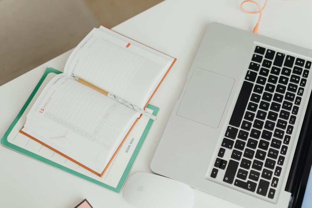 A home desk with a laptop, notebook, and wall calendar set up for an evening study session.