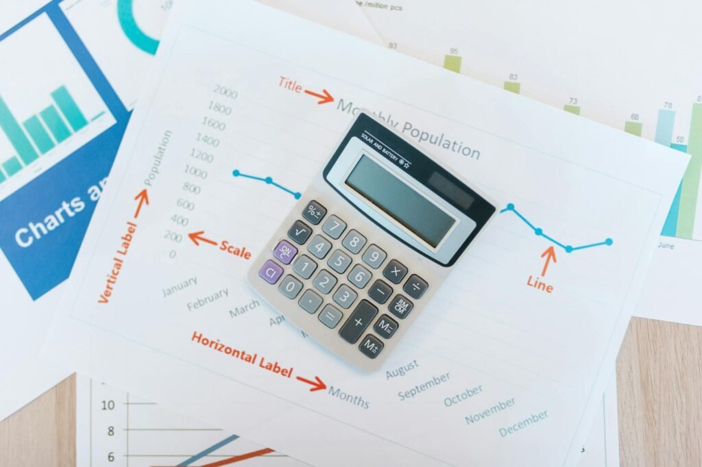 A calculator, monthly calendar, and a small stack of sorted household bills on a desk