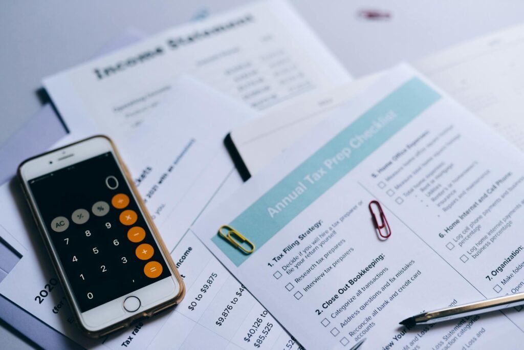 A calculator, receipts, and smartphone showing a budgeting review on a kitchen counter.