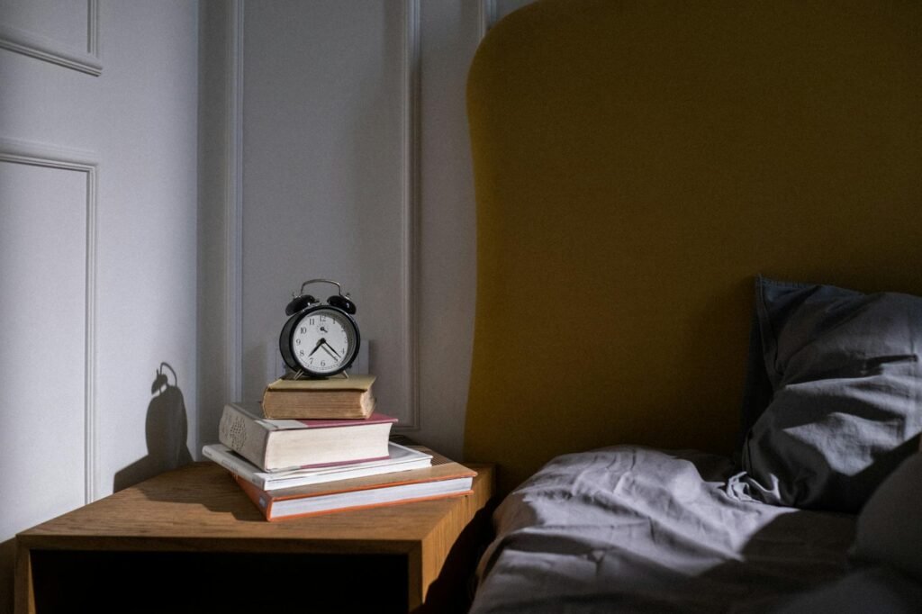 Morning sunlight coming into a bedroom with an alarm clock on a bedside table